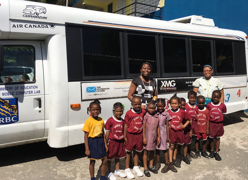 A group of students and teachers standing outside a white bus