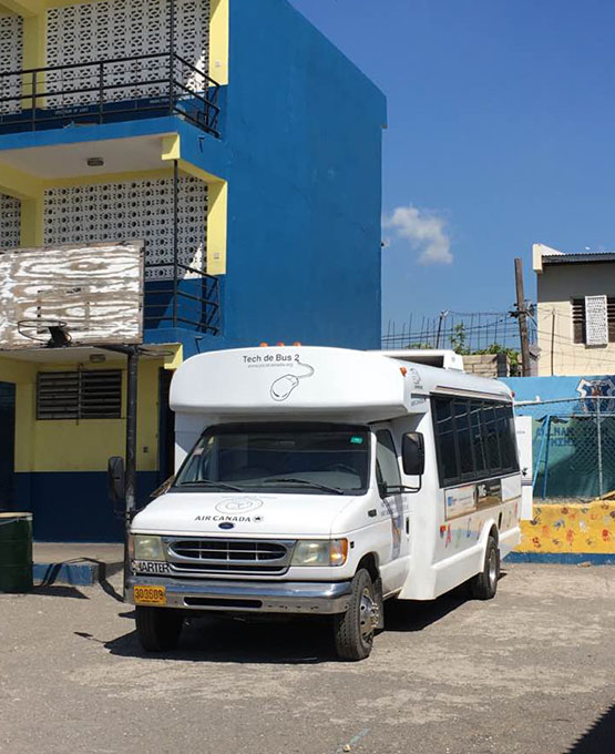 A close up of a white bus in front of a blue and yellow building