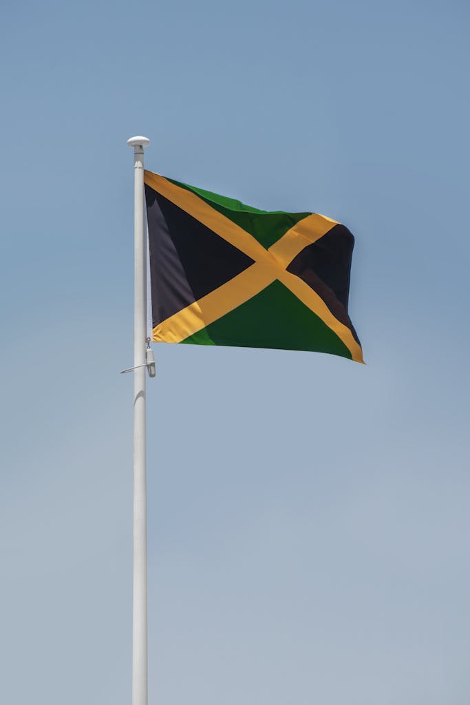 The Jamaican national flag waving proudly against a clear blue sky.