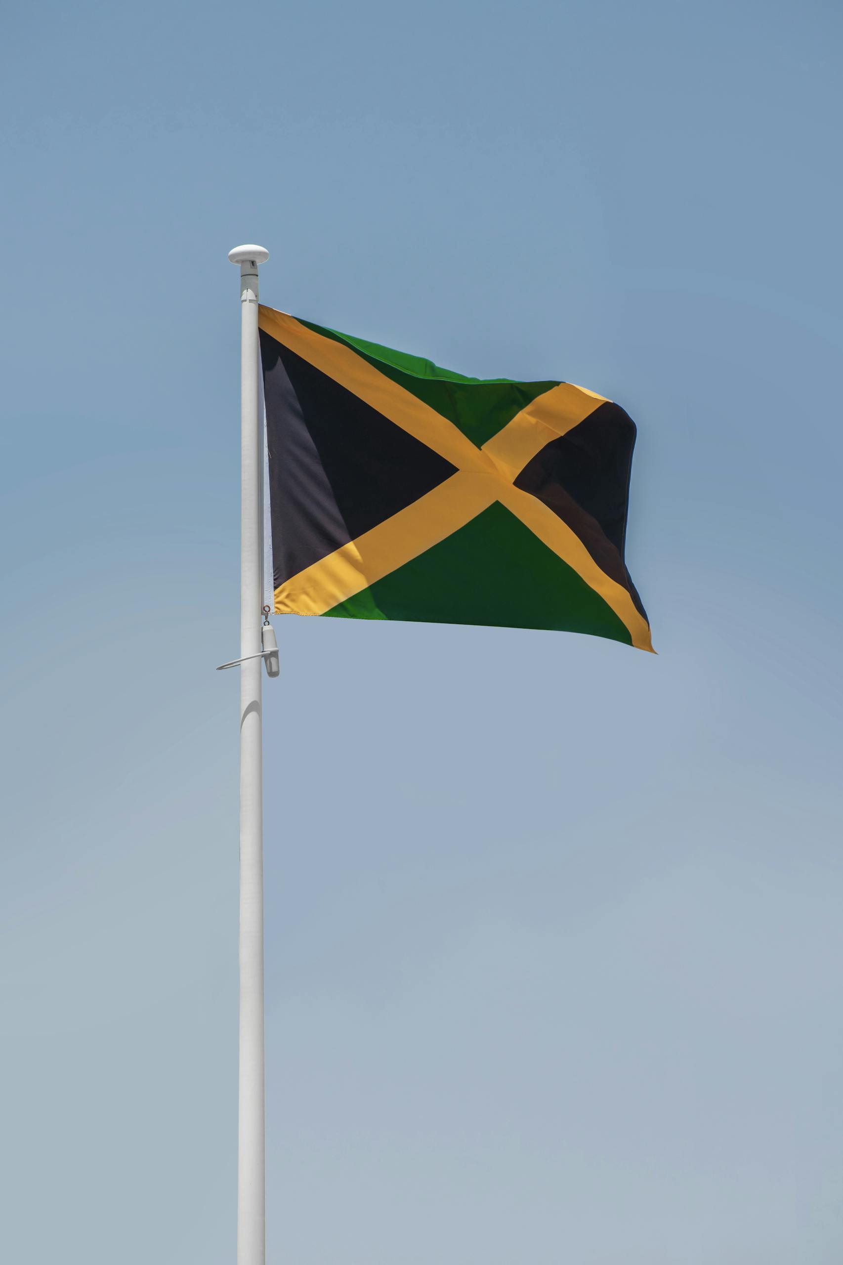 The Jamaican national flag waving proudly against a clear blue sky.