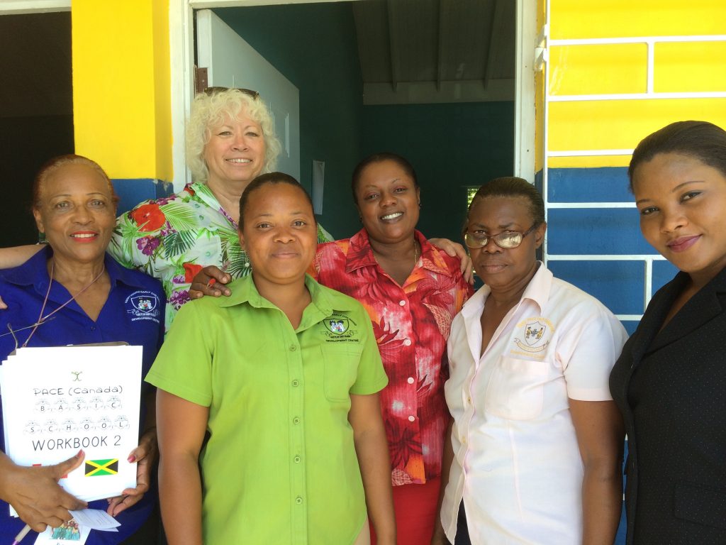 PACE member Diana Burke with teachers smiling on the terrace outside of a school