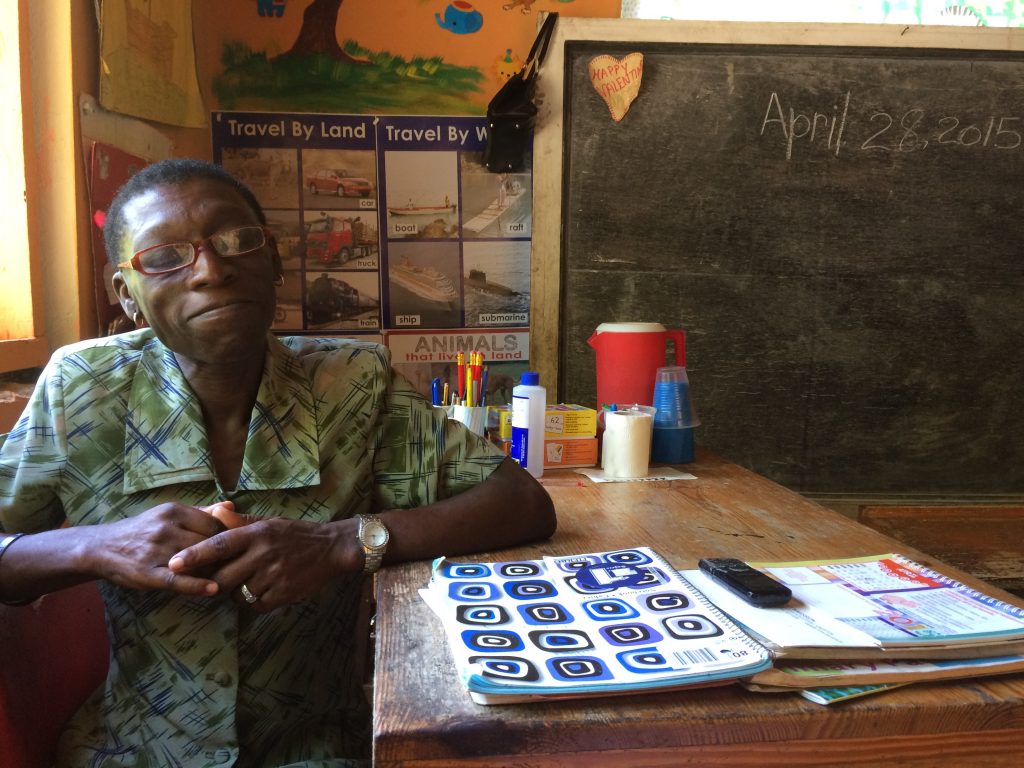 A teacher sitting at their desk with teaching supplies around.